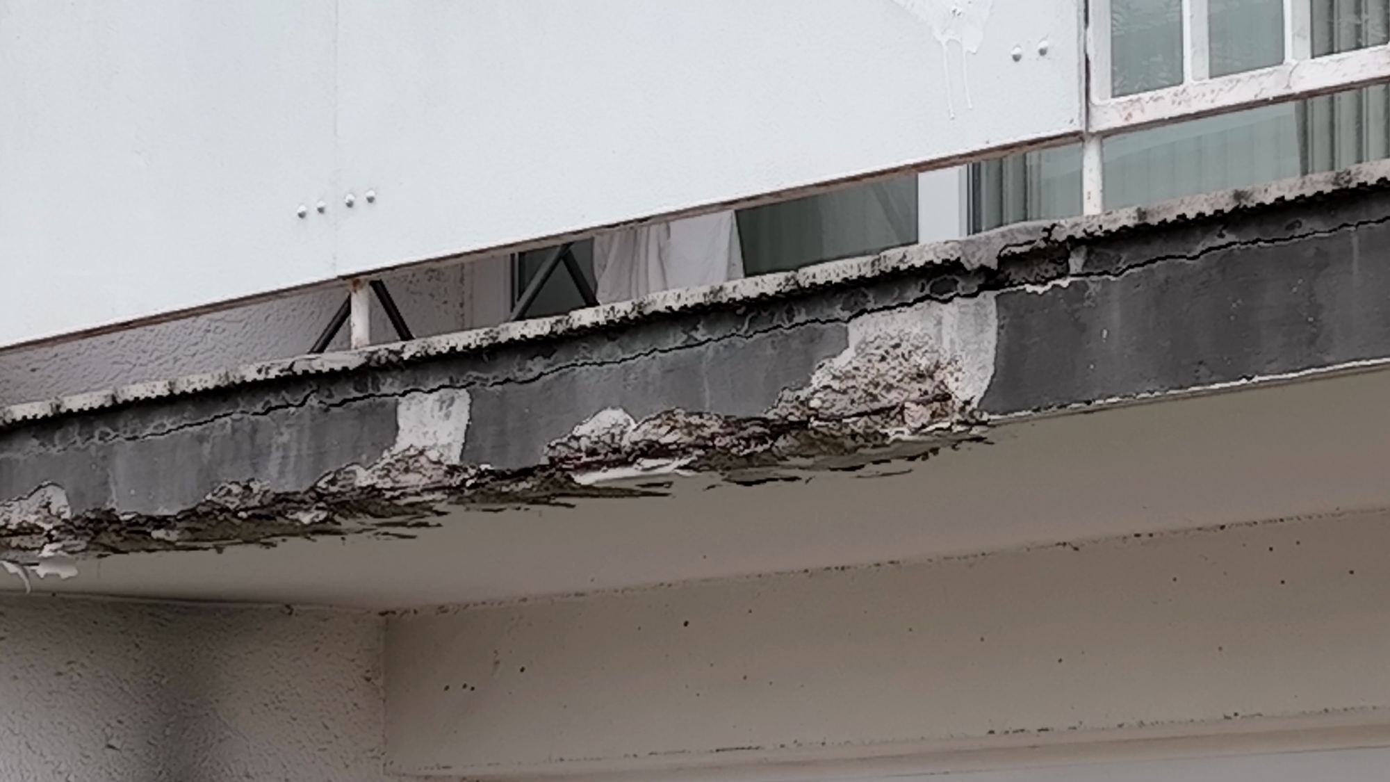 Die Balkonplatte aus der Nähe mit abgeplatztem Beton an der Kante